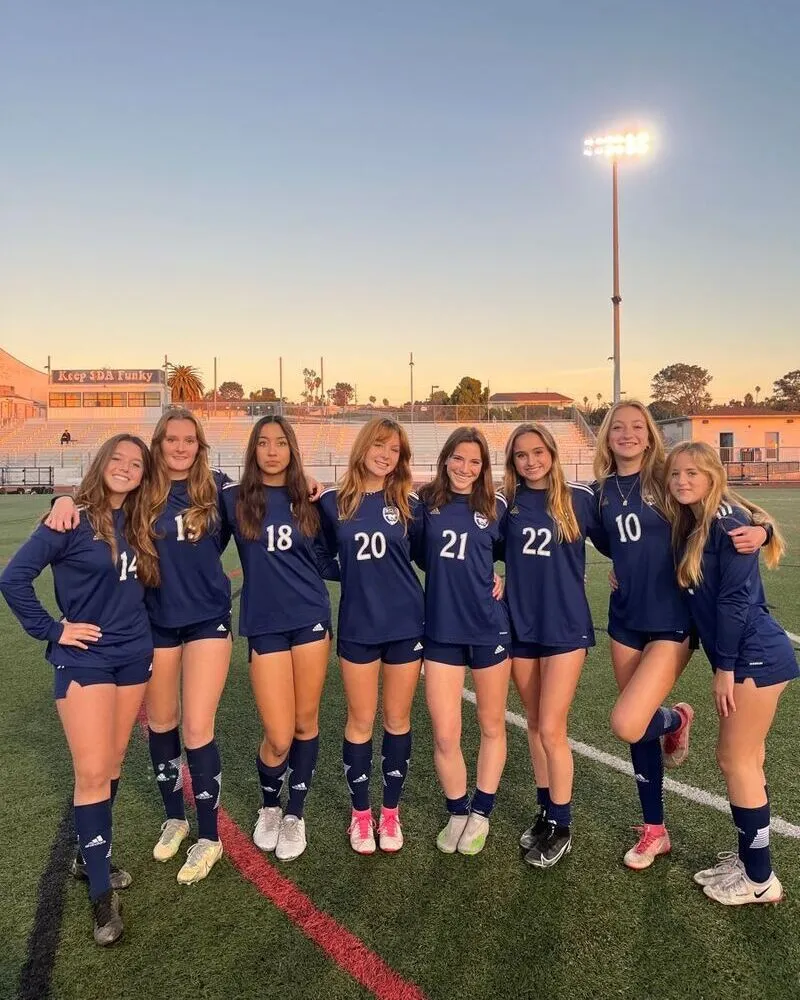 girls local club team wearing blue soccer uniforms standing in ground