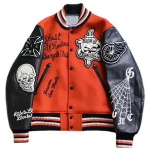 A bold orange wool varsity jacket with asymmetrical sleeves one black leather and one white with a spiderweb print featuring multiple biker-style patches like 'Ghost Wheelers' and skull graphics.