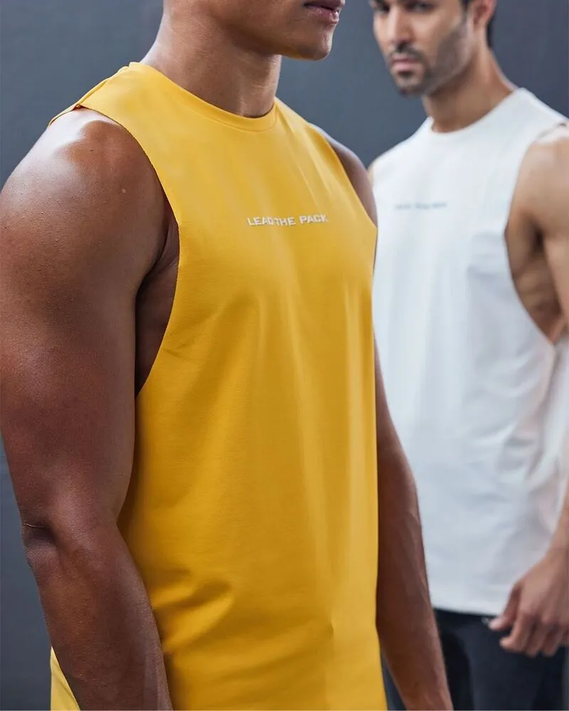 A close-up of two men wearing sleeveless muscle tank tops; the man in the foreground is in a vibrant yellow tank with the slogan lead the pack printed on the chest, while the man in the background wears a similar white version.